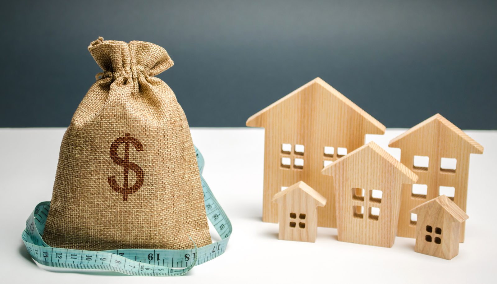 photo of a money bag next to a house representing the cost of property